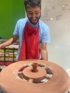 A boy is making cup using clay.