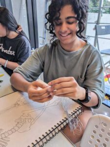 A girl is making something using thread.